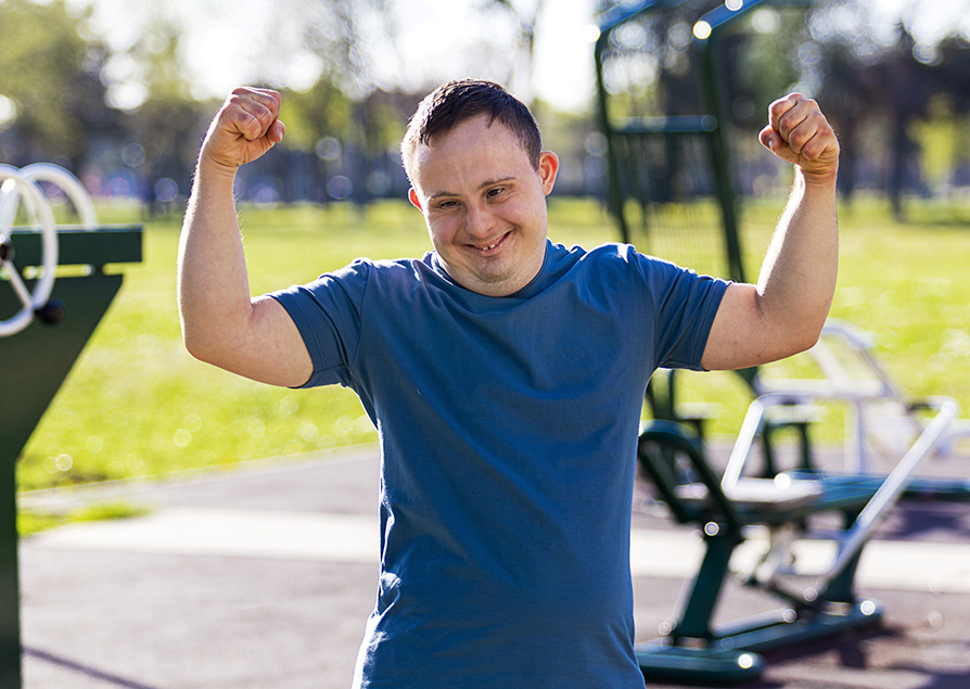 Young man with down syndrome working out at outdoor gym